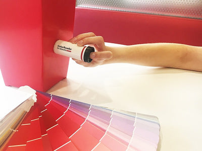 A person using the Datacolor Color Reader on a red object to determine the closest paint color match, available at Regal Paint Centers in MD, VA & Washington, DC metro.